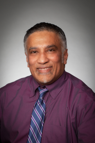 A photo of a man wearing a purple shirt and striped tie.