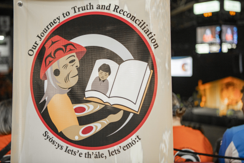 A drawing of an Elder reading a book. Text around the image reads: Our Journey to Truth and Reconciliation. 