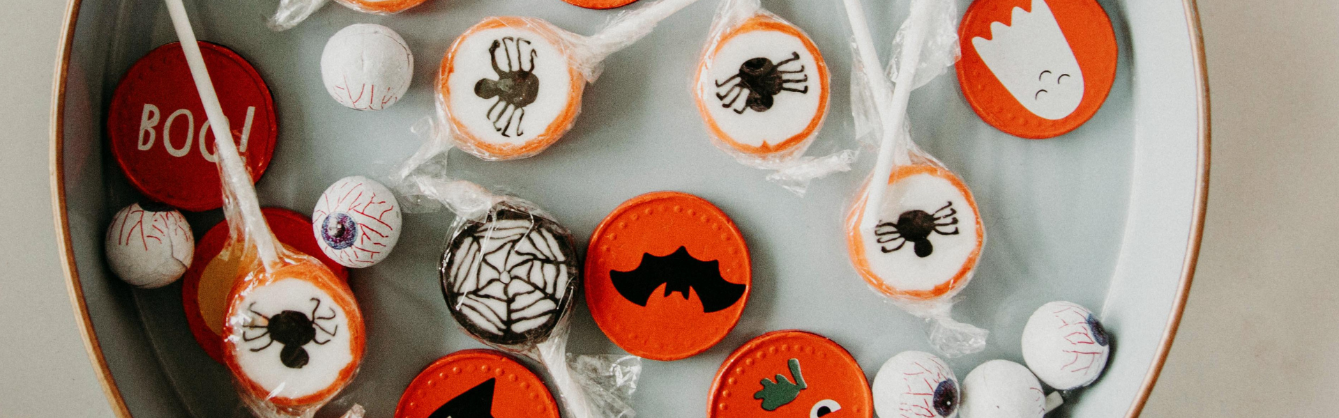 A white bowl of orange, black and white Halloween candy. 