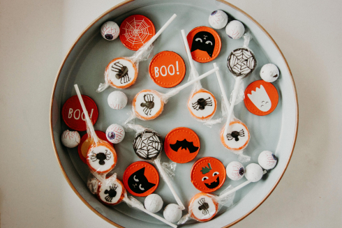 A white bowl full of orange, black and white Halloween candy. 