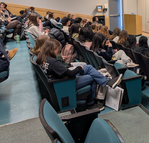 Students in a classroom theatre writing notes. 
