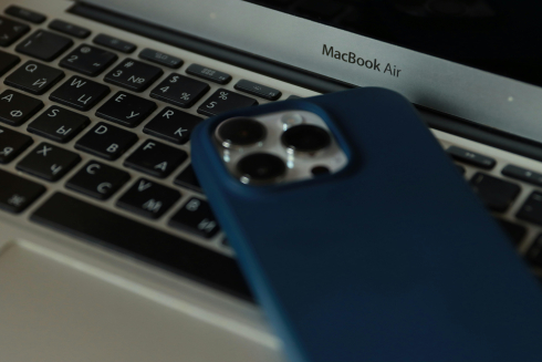 A blue cell phone rests on a laptop keyboard. 