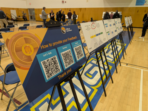 A row of posterboards on stands. In the background people are talking in groups. 