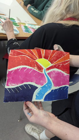 A student displays a vibrant red, purple and pink print from a class with senior citizens. 