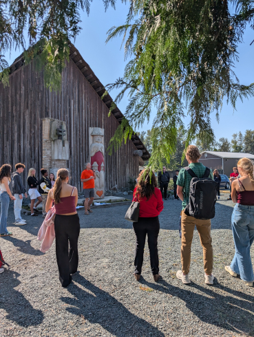A group of students is gathered around a person in an orange shirt. 