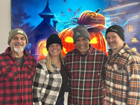 Four people are dressed in plaid shirts and toques for Halloween. 