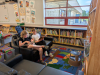 Two young people sit on a couch and read in a library. 