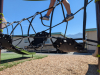 A child walks across a rope ladder on a playground. 