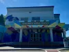 A brightly painted school with a rainbow crosswalk. 