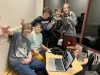 Five students gather around a computer and smile at the camera. 
