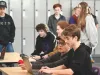 A group of students gather around a computer. 