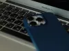 A blue cell phone rests on a laptop keyboard. 